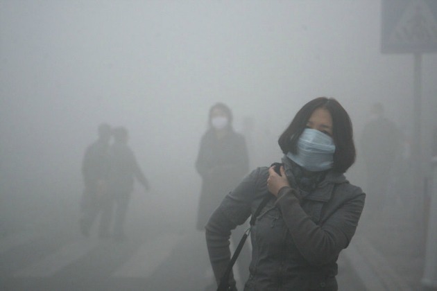 Védőmaszkos lány sétál Peking utcáin, ahol a levegőben található szennyező mikrorészecskék száma 40-szerese a nemzetközi egészségügyi határértéknek